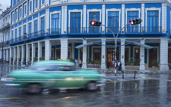 Cuba, Havana. A classic car passes by in a rainstorm the city