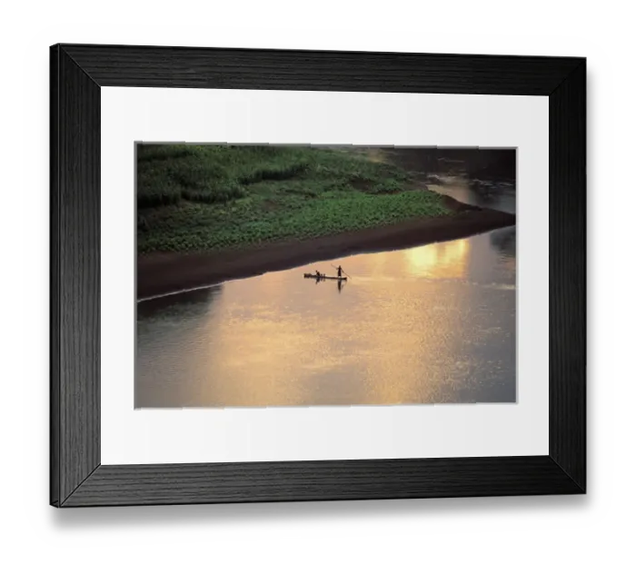 Framed Print : The sun sets on some Karo men piloting a dugout raft across the Omo River, near their