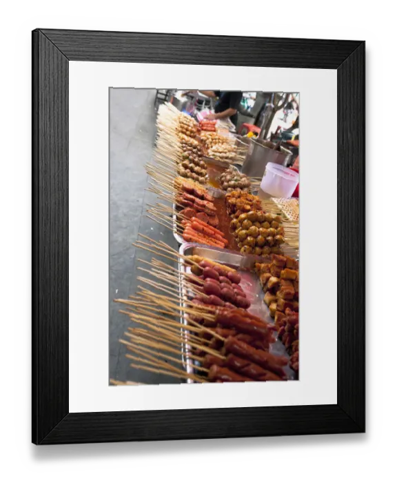 Framed Print : Bangkok, Thailand - Tilted view of a street vendor selling various Thai foods on wood skewers Framed Print : Bangkok, Thailand - Tilted view of a street vendor selling various Thai foods on wood skewers