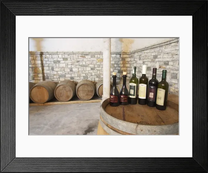 Framed Print : Bottles on top of a barrel, with barriques in the background: Raki me Arra grappa type of spirit