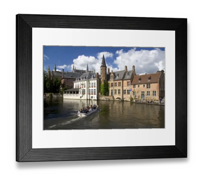Framed Print : Tourists ride in a canal boat at the city of Bruges in the province of West Flanders Framed Print : Tourists ride in a canal boat at the city of Bruges in the province of West Flanders