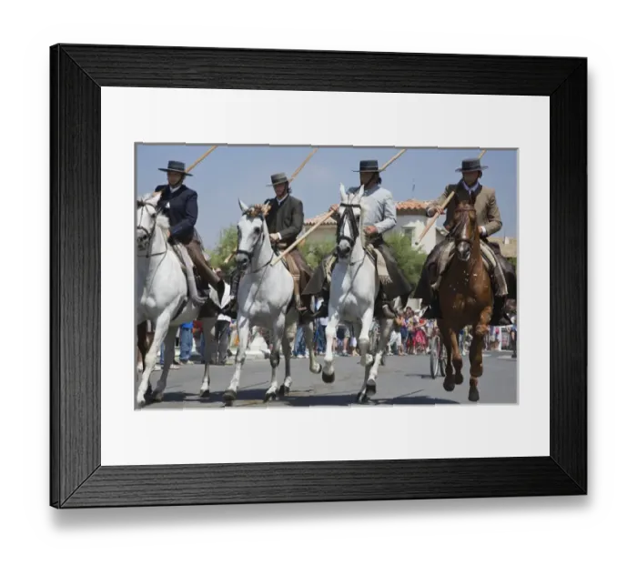 Framed Print : France, Camargue, Saintes-Maries-de-la-Mer. Horseman and horses ride down the main Framed Print : France, Camargue, Saintes-Maries-de-la-Mer. Horseman and horses ride down the main