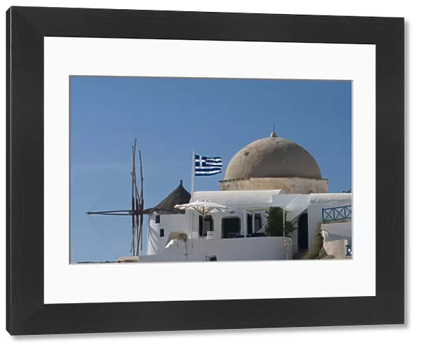 Europe, Greece, Santorini, Thira, Oia. Windmill and church dome with a Greek flag flying