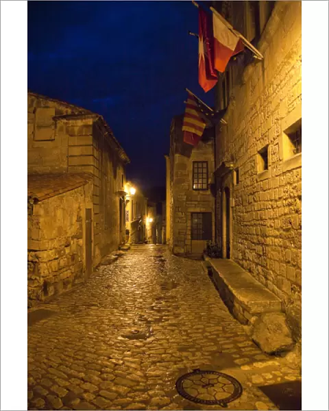France, Provence, Les Baux-de-Provence. Flags over deserted street inside castle at night