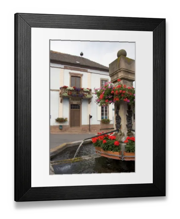 Framed Print : Water fountain with red geraniums in the village of Roschwihr, Eastern France