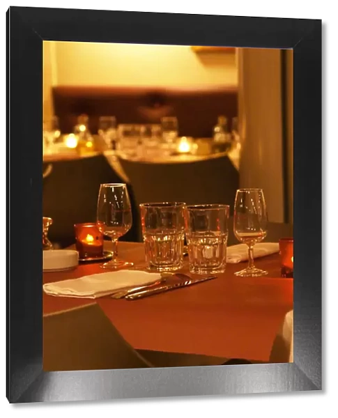 Interior of The restaurant Brunel at night. Tables with glasses, knives, ofrks, glasses