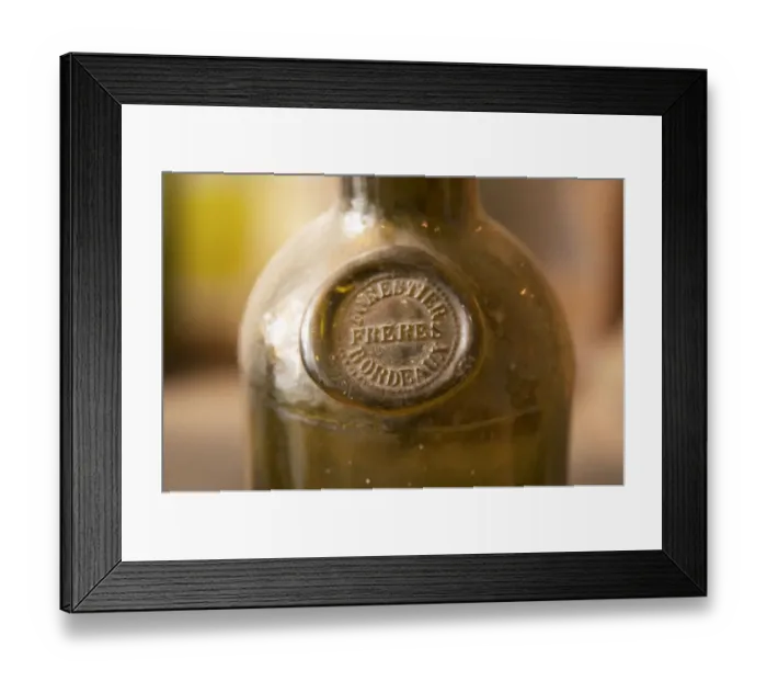 Framed Print : An old antique dusty wine bottle with a moulded seal on the shoulder of the bottle