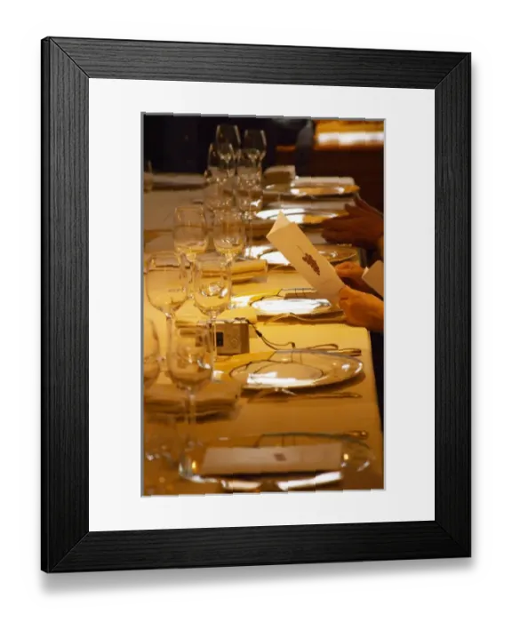 Framed Print : A guest holding up and reading the menu in anticipation of the meal. In the restaurant