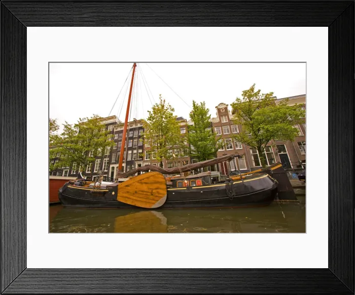 Framed Print : Unusual sail boat with large wooden paddle on a canal lined with homes