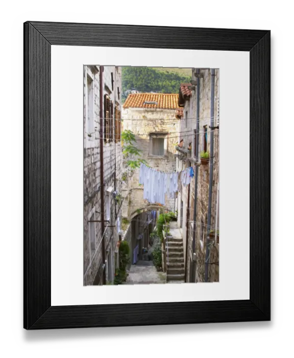 Framed Print : A narrow street leading down with steep steps, clothes lines hanging across the street Framed Print : A narrow street leading down with steep steps, clothes lines hanging across the street
