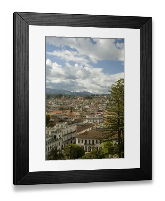 Framed Print : Historic buildings with red tile roofs, palm trees, and mountains in distance, Cuenca