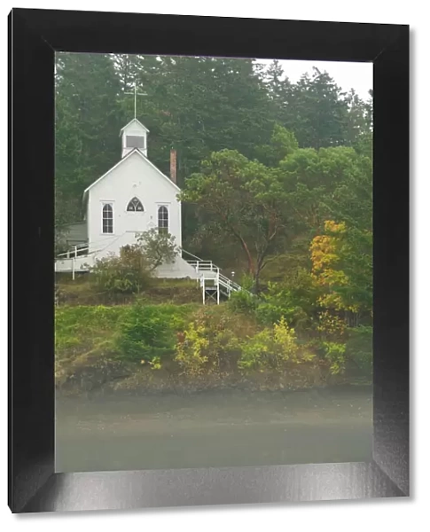 USA, WA, San Juan Island. Fall color and fog accent quaint Roche Harbor chapel
