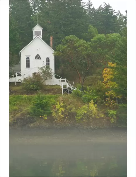 USA, WA, San Juan Island. Fall color and fog accent quaint Roche Harbor chapel