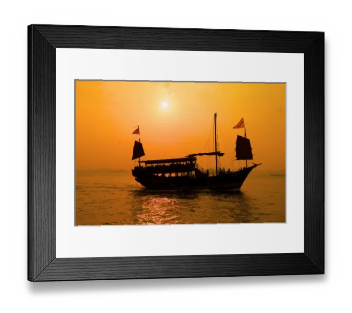 Framed Print : A junk sails through Aberdeen harbor near Hong Kong at sunset