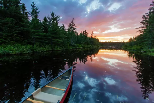 A canoe at sunrise on Little Berry Pond in Maines Northern Forest. Cold Stream watershed