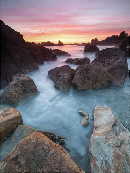 North America, USA, Oregon. Sunset and incoming tide at Harris Beach State Park, ORrocks at arch