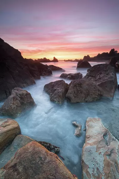 North America, USA, Oregon. Sunset and incoming tide at Harris Beach State Park, ORrocks at arch