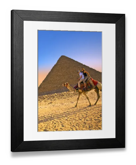 Framed Print : Tourists ride a camel in front of the Great Pyramids of Egypt in Cairo on the Giza Framed Print : Tourists ride a camel in front of the Great Pyramids of Egypt in Cairo on the Giza