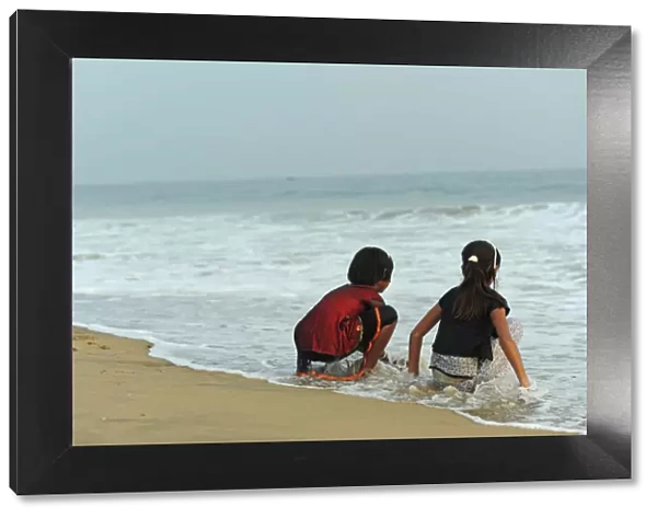 India, Odisha, Puri, two girl friends having fun with the waves of the ocean