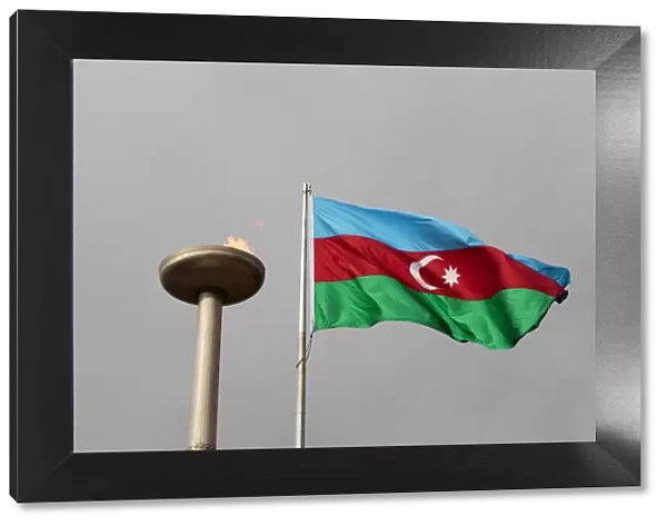 Azerbaijan, Baku. An Azerbaijan flag waves near a memorial flame