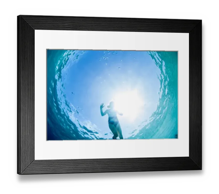 Framed Print : Looking up at a woman snorkeling in clear blue water near Staniel Cay, Exuma, Bahamas