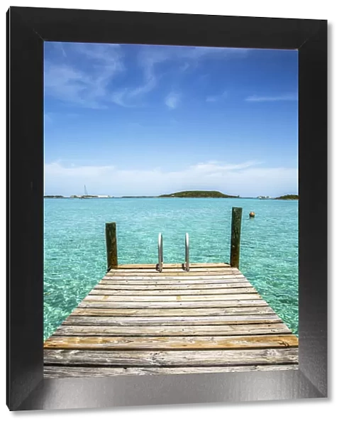 Vertical photo with a dock in the foreground, clear water and blue sky in the background