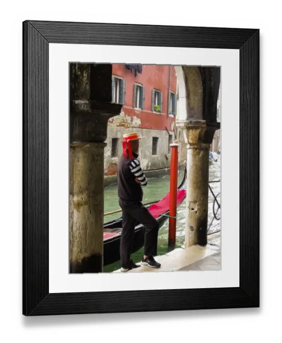 Framed Print : Venice, Italy. Gondolier man looks out onto the canal next to his gondola