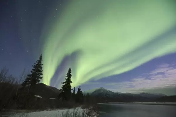 Curtains of green aurora borealis dance in the sky over the Middle Fork of the Koyukuk