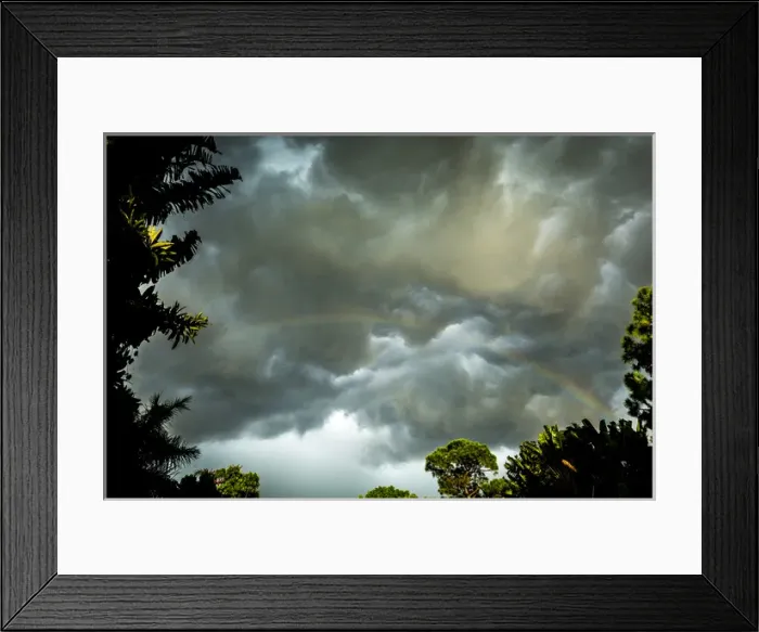 Framed Print : Storm clouds approach in this photograph while a rainbow is illuminated by sunrays Framed Print : Storm clouds approach in this photograph while a rainbow is illuminated by sunrays