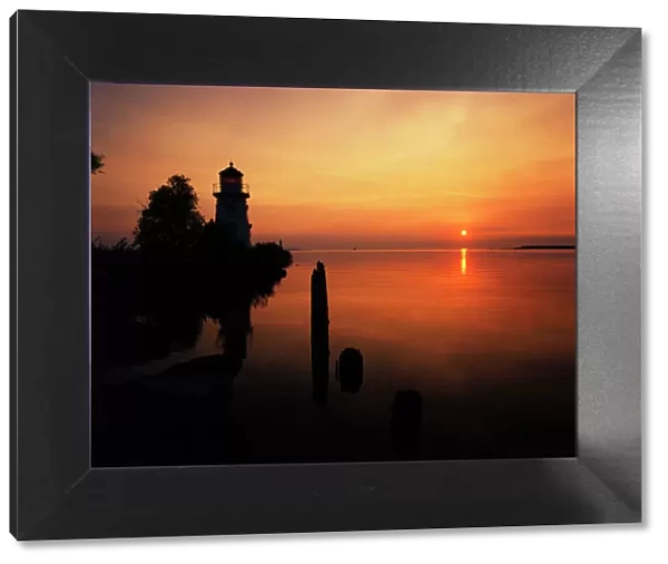 USA, Michigan, Cheboygan, View of sea and lighthouse at sunset