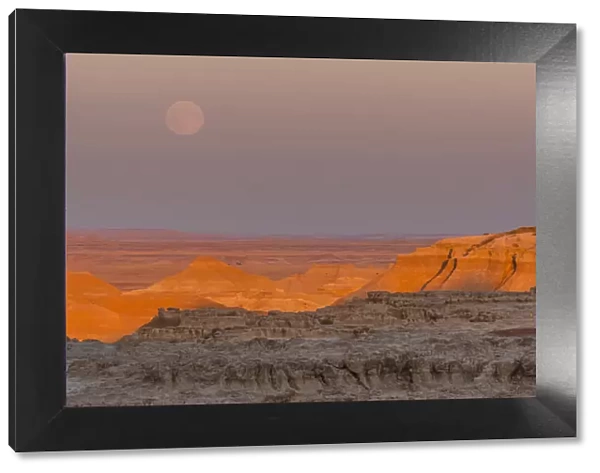 USA, South Dakota, Badlands National Park. Moonrise over rugged landscape at sunset