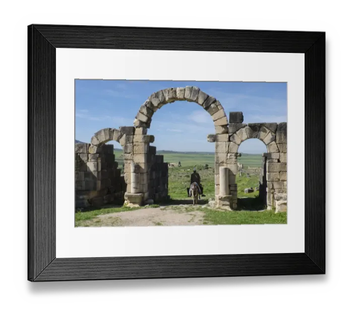 Framed Print : Africa, Morocco. A man on a donkey passes under stone columns and arches at the roman Framed Print : Africa, Morocco. A man on a donkey passes under stone columns and arches at the roman