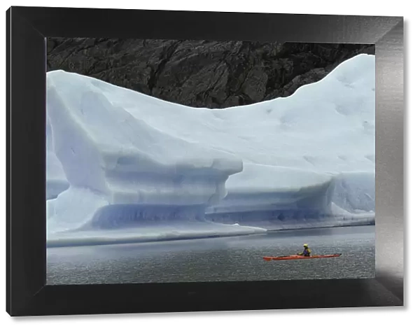 Kayakers exploring Grey Lake amid large iceberg, Torres del Paine National Park