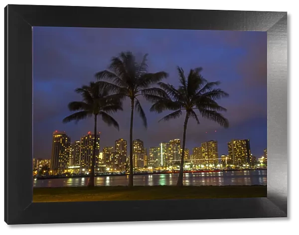 USA; Hawaii; Honolulu; Palm Trees with the night lights of Honolulu