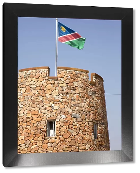 Africa, Namibia, Etosha National Park. Namibian flag flies over brick tower at park entrance