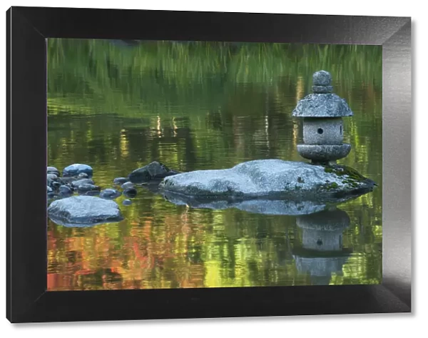 Concrete lantern on a rock in a pond surrounded by reflections of Fall colors in the water