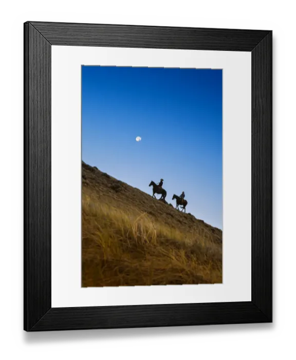 Framed Print : Two wranglers riding horses up a hill with full moon in backround at blue hour