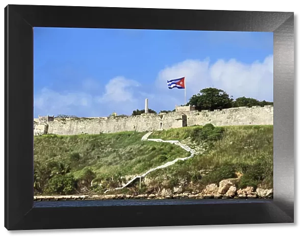 Cuba, Havana. Fortress wall and Cuban flag at San Carlos de la Cabana fortress in