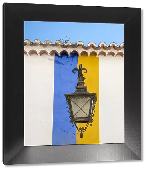 Europe, Portugal, Obidos. Wrought iron lantern hanging from a colorful stripped wall