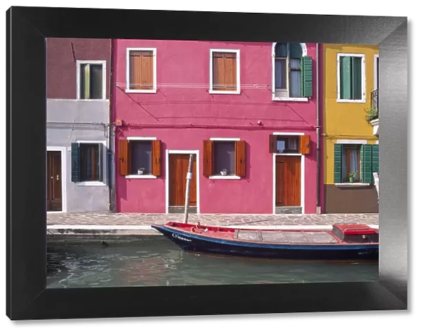 Italy, Burano. Colorful house exteriors and boat in canal