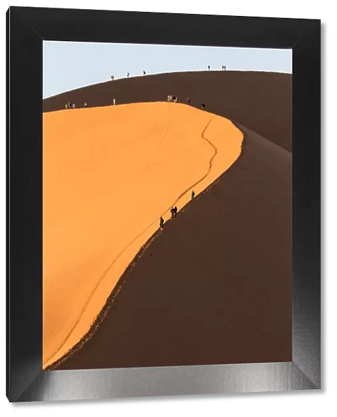Africa, Namib Desert. Hikers climbing the red sand dune in Namibia