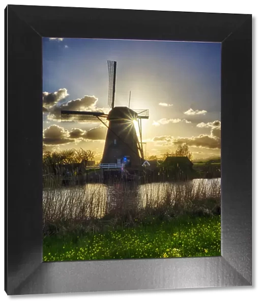 Netherlands, Kinderdijk. Windmill along the canal at sunset