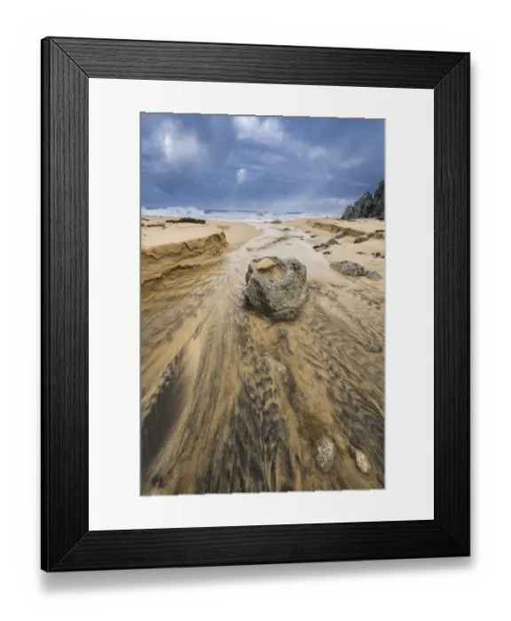 Framed Print : Low angle of a stream flowing around a rock heading into the ocean with stormy skies Framed Print : Low angle of a stream flowing around a rock heading into the ocean with stormy skies