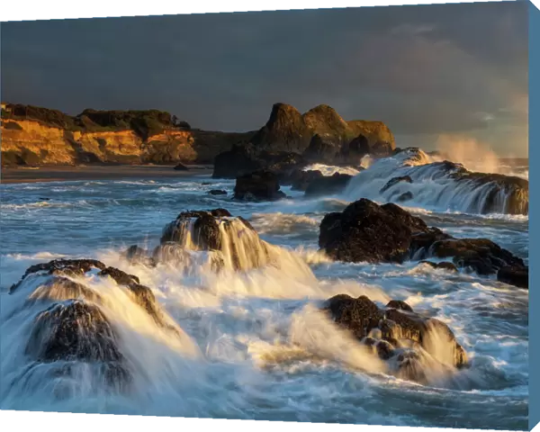 Waves crashing on rocks and washing down the sides at sunset