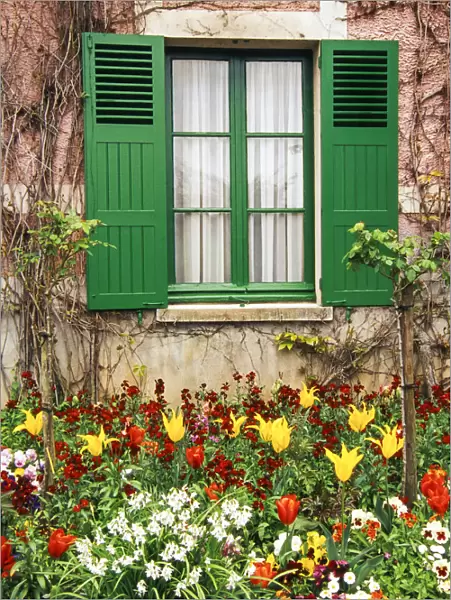 Green shutters at a window overlooking a garden in France