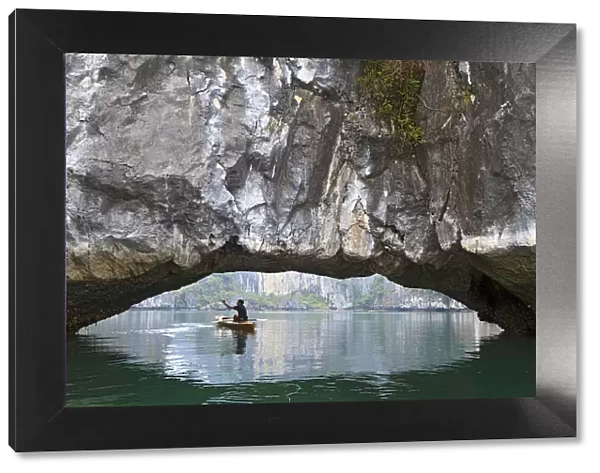 Ha Long Bay, Vietnam. View of kayaker through limestone arch