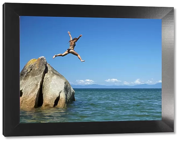 Girl jumping off rock, Mosquito Bay, Abel Tasman National Park, Nelson Region, South Island