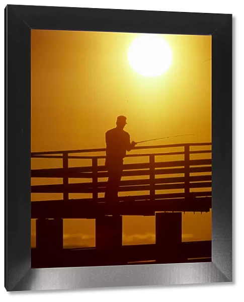 Silhouette of man fishing from a pier