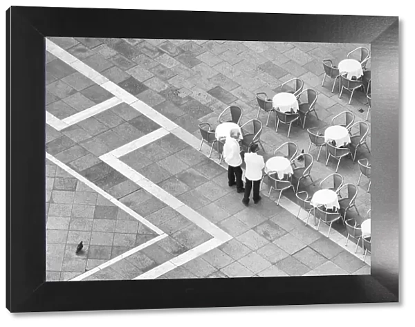 Italy, Venice. Black and white looking down on waiters in San Marco Square from Campanile