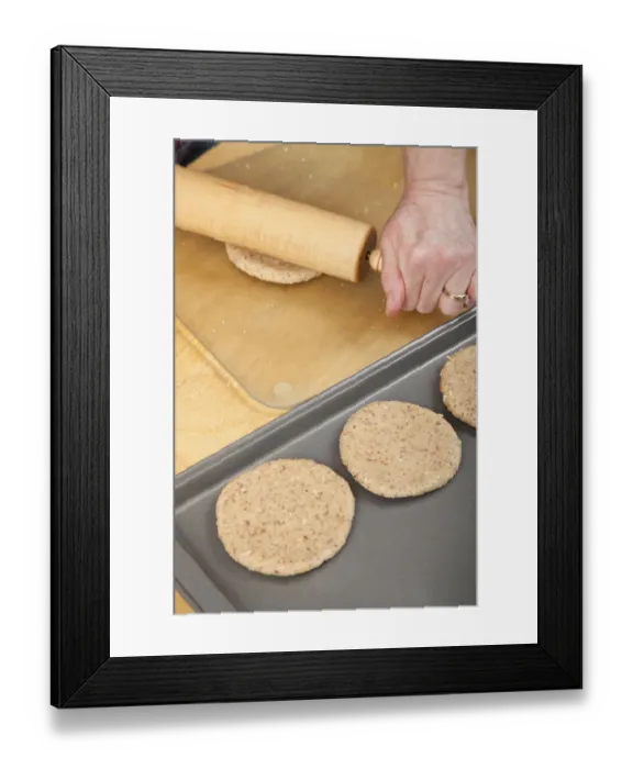 Framed Print : Woman rolling multigrain bread dough into circles to make hamburger buns. (MR) Framed Print : Woman rolling multigrain bread dough into circles to make hamburger buns. (MR)
